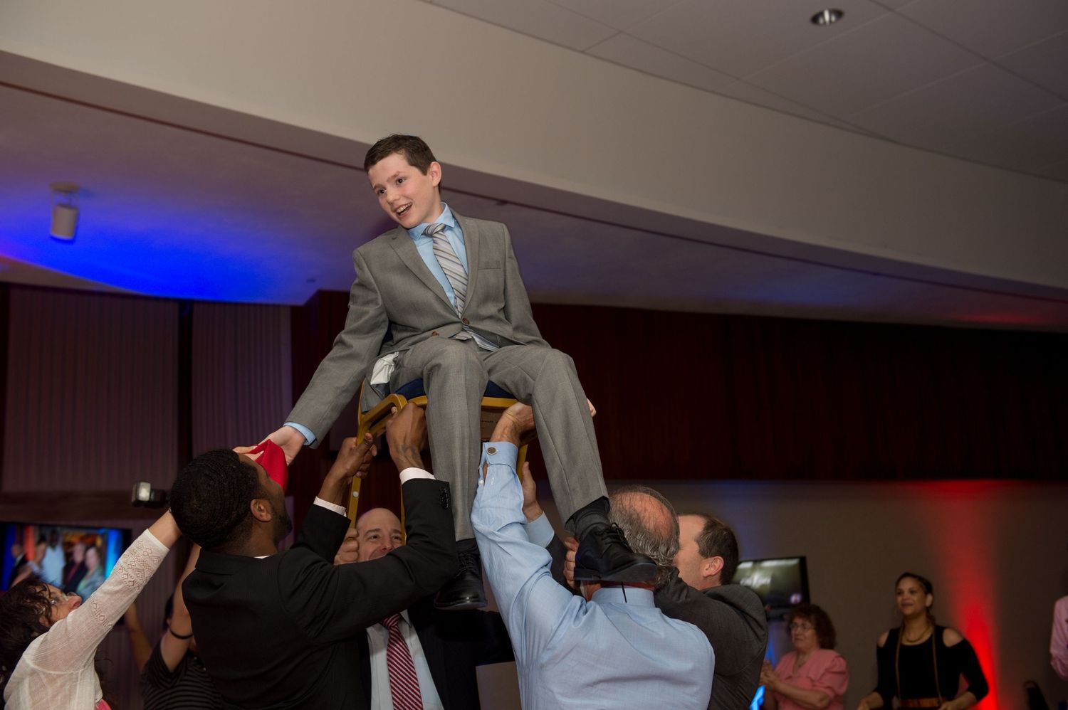 Wedding reception guests lifting and celebrating with the couple during a fun dance floor moment.