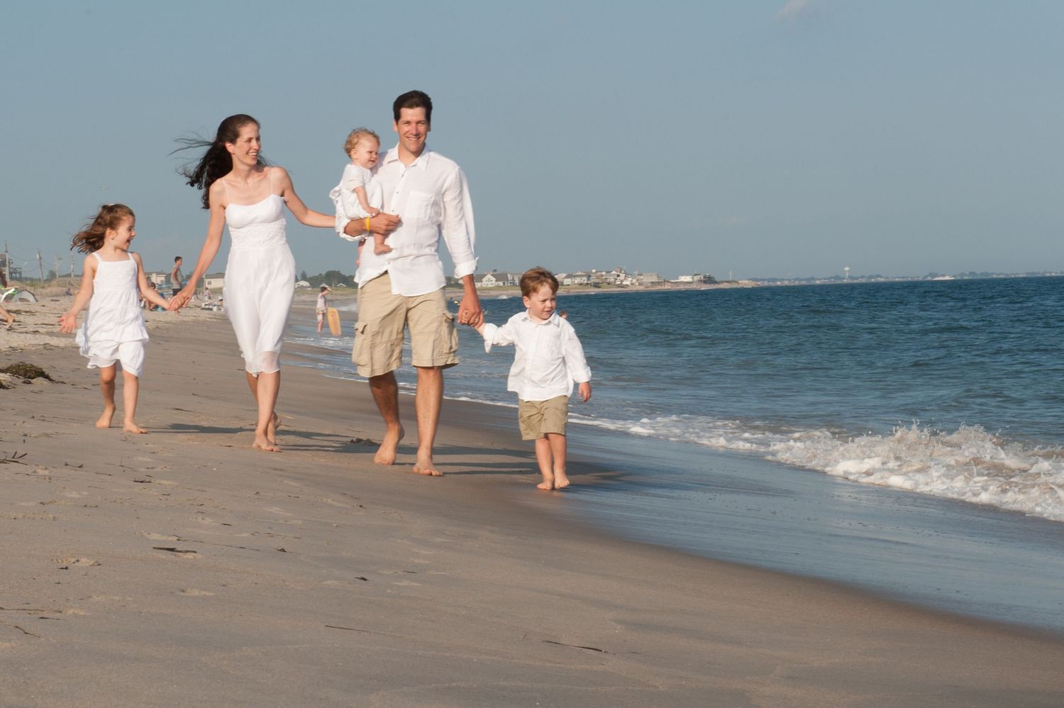 Family walking and playing together along a scenic beach shoreline.