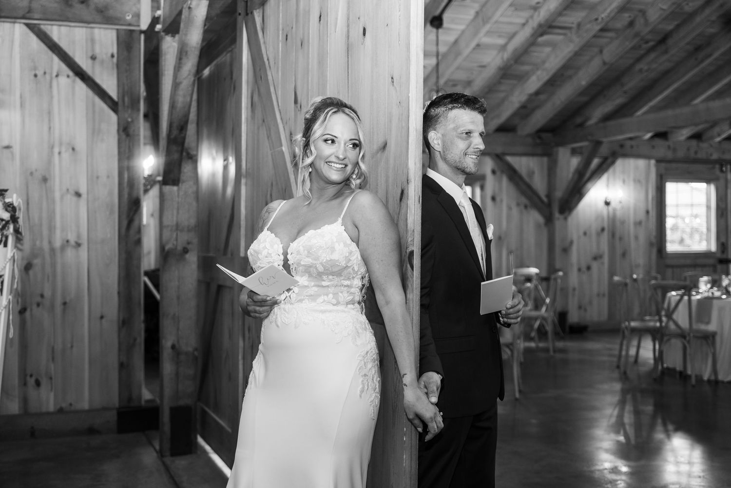 A rustic wooden barn interior decorated for a wedding ceremony with natural lighting.