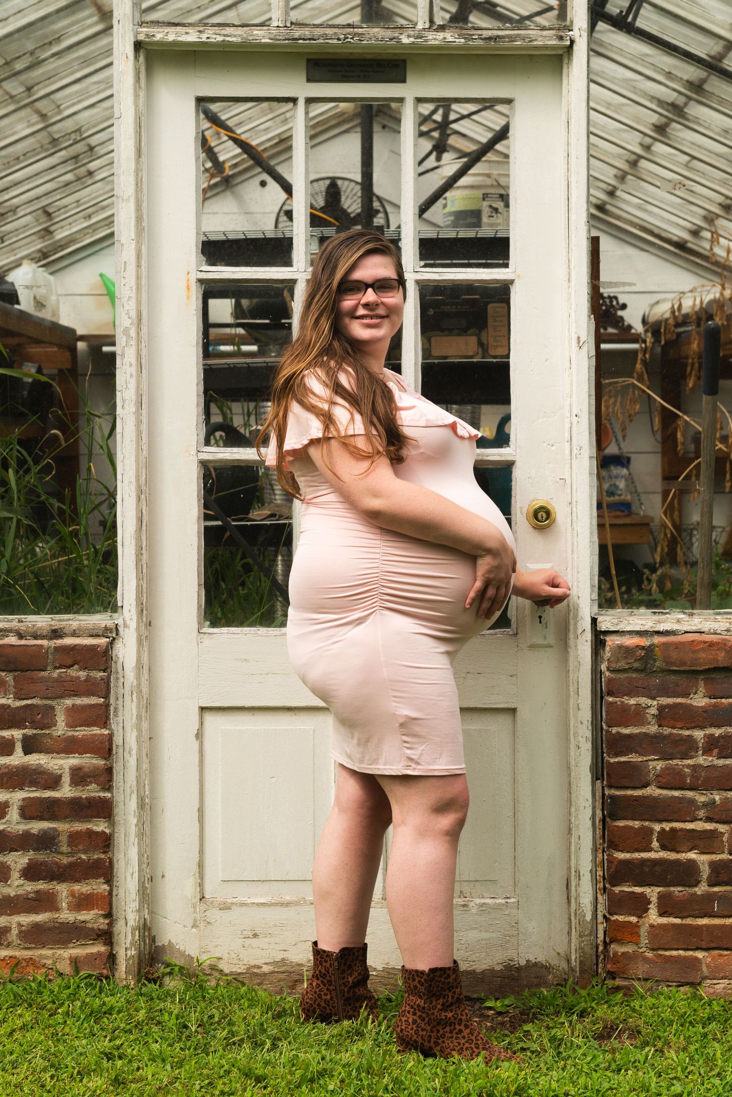 Artistic maternity poses captured in front of a vintage greenhouse structure.