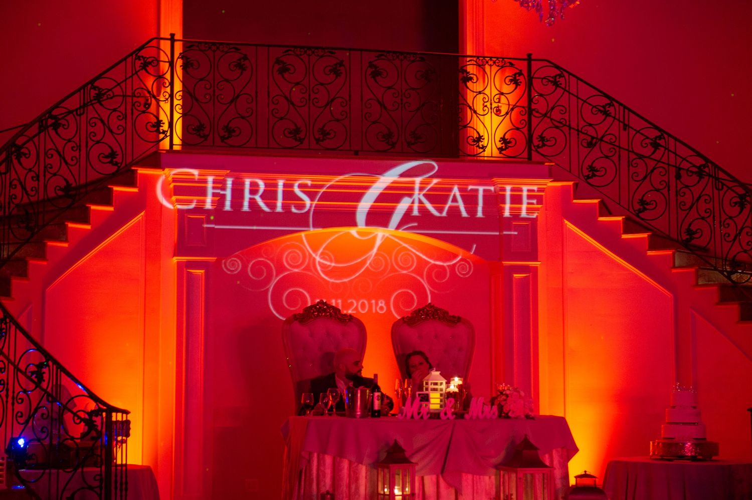 Custom monogram lighting display with names projected in elegant script against red-lit wall decor.