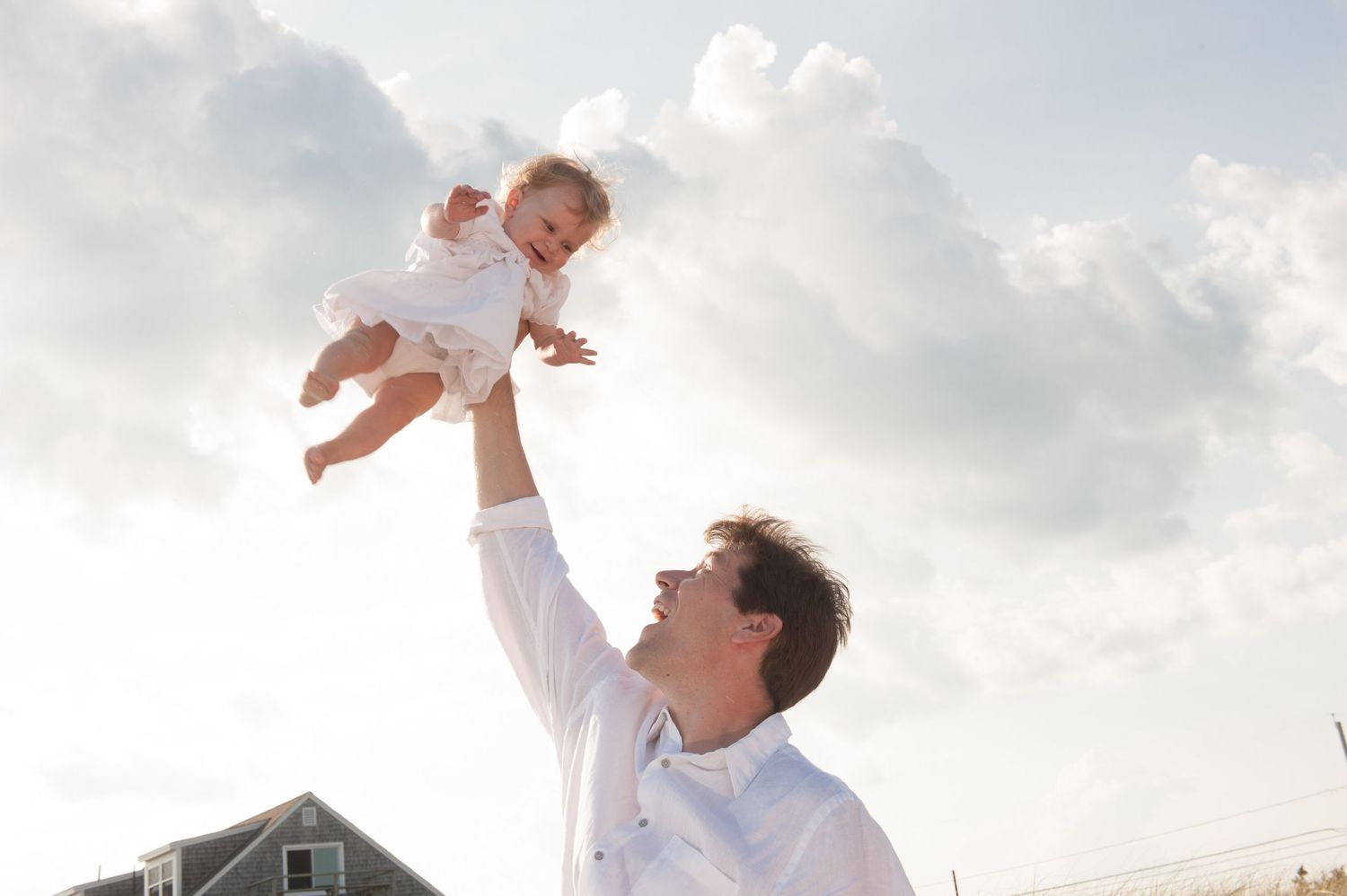 Family enjoying a playful moment together against a bright sky backdrop.