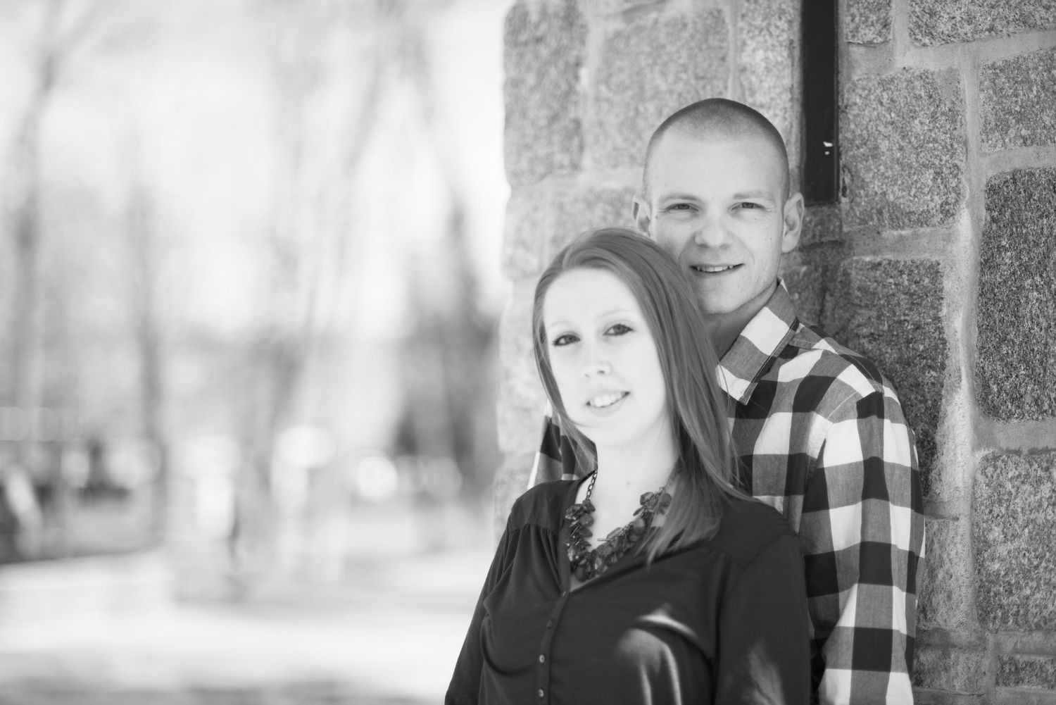 Winter engagement photos of couple in black and white buffalo plaid outdoors.