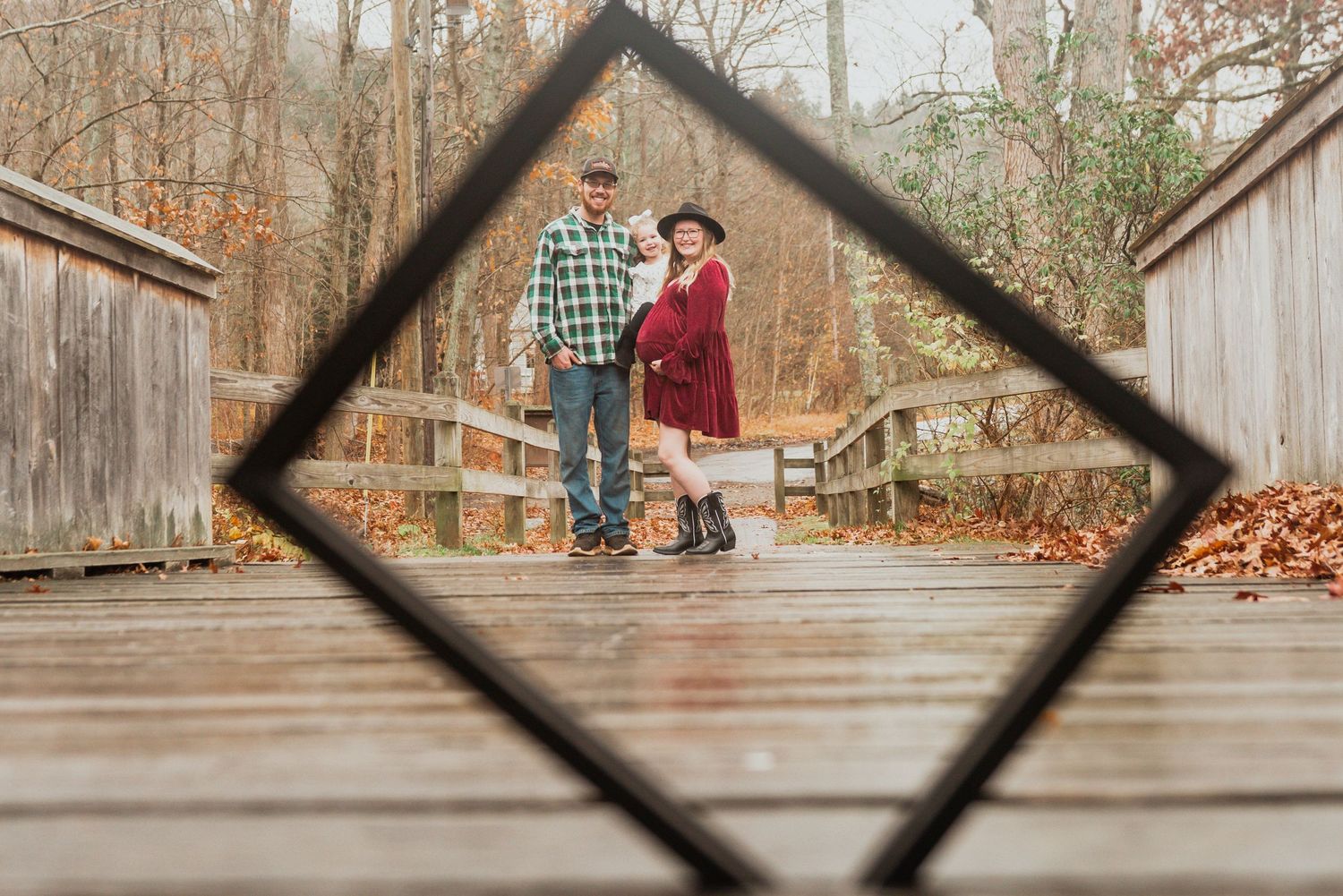 Diagonal wooden beams frame a rustic outdoor scene with autumn leaves.