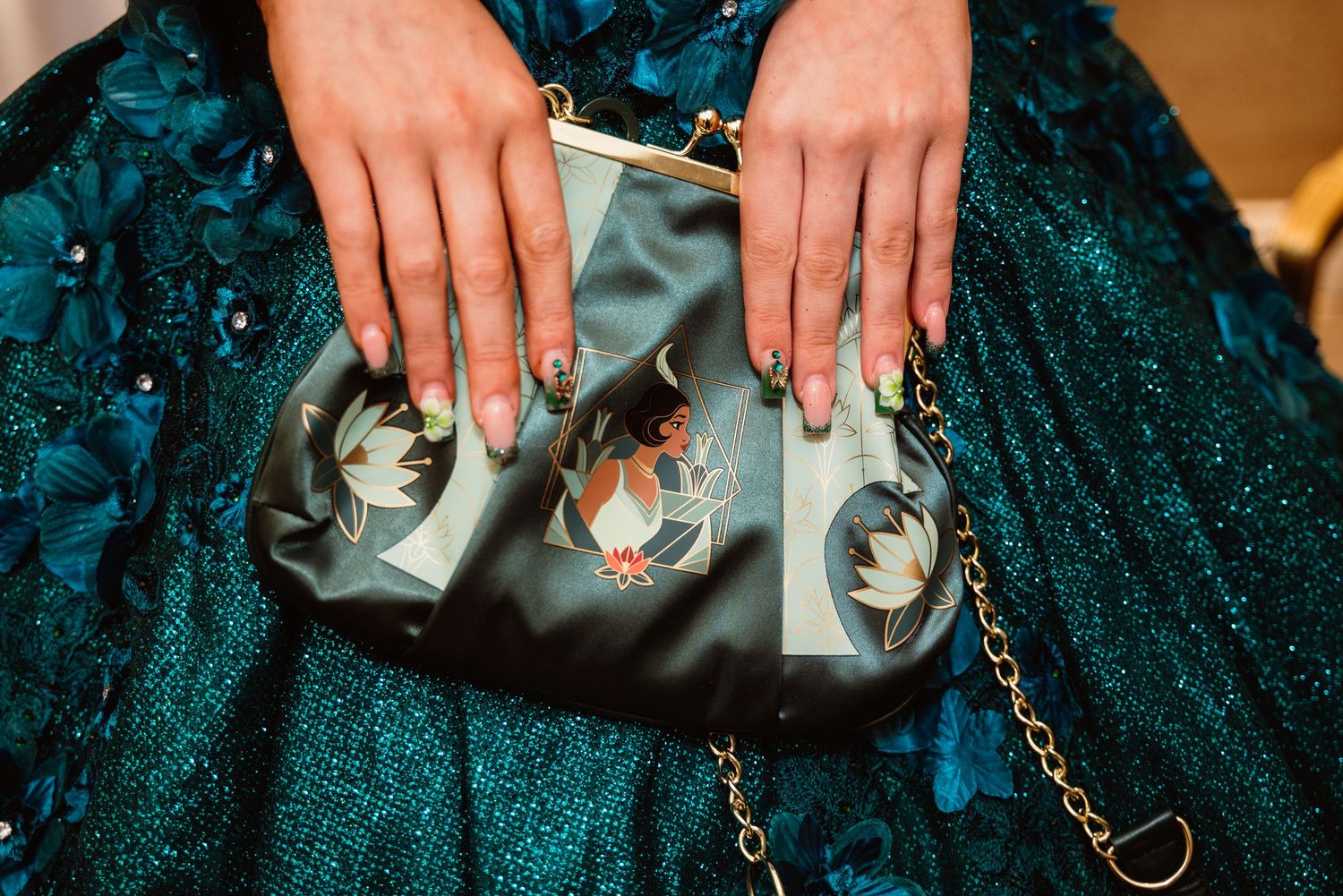 Hands holding silver clutch purses against a sparkly teal evening gown.