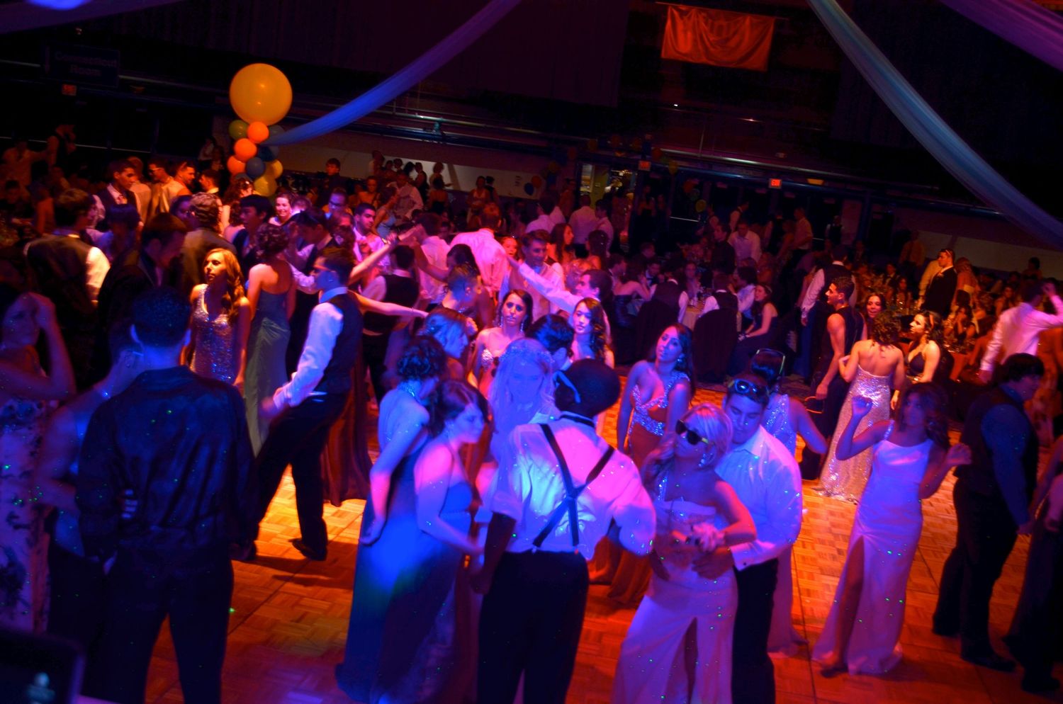 Dance floor filled with wedding guests under dramatic purple and blue lighting.