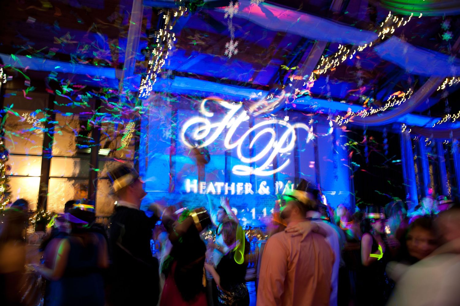 A wedding reception venue with blue lighting and a custom monogram projection displaying names.