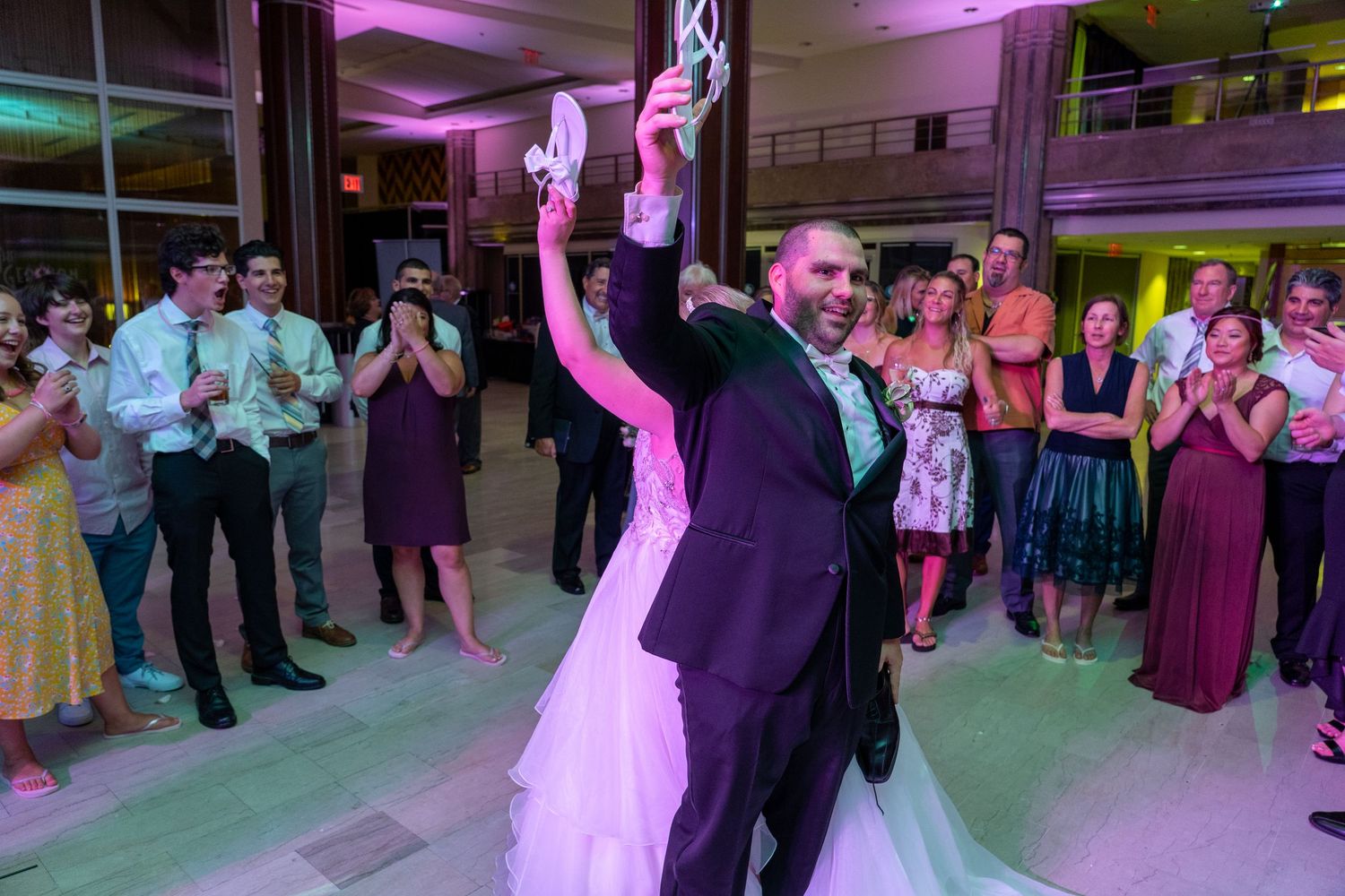 Wedding guests dance and celebrate on a colorful illuminated dance floor during an evening reception.