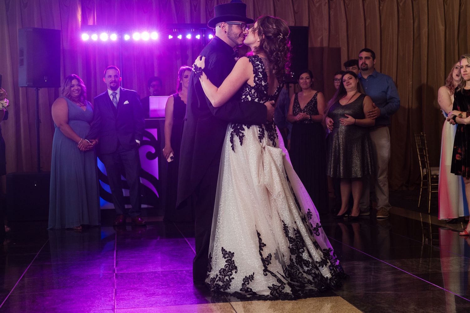 Wedding reception dance floor illuminated with purple lighting and guests dancing.