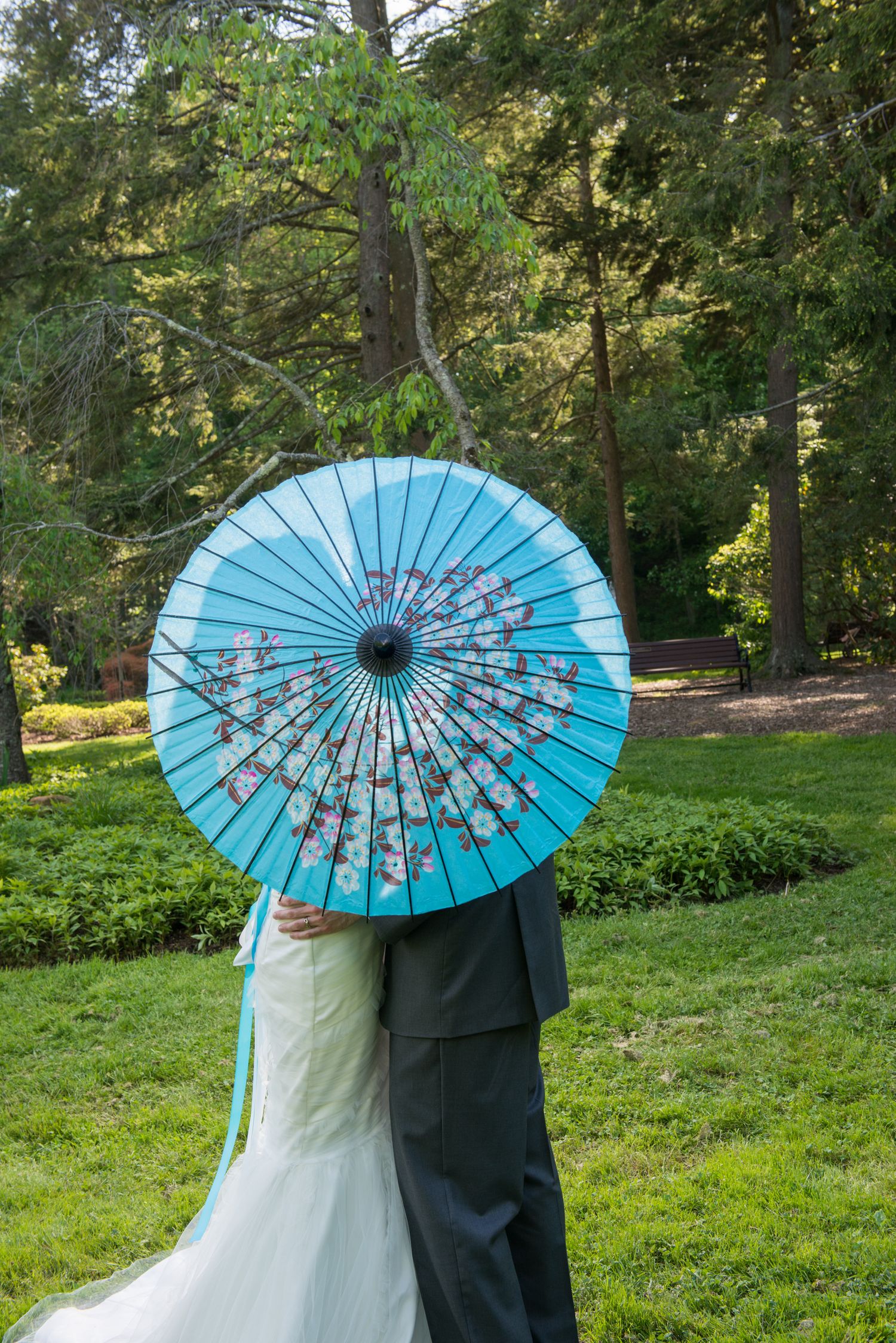Couple posing with blue parasol umbrella in a lush garden setting.