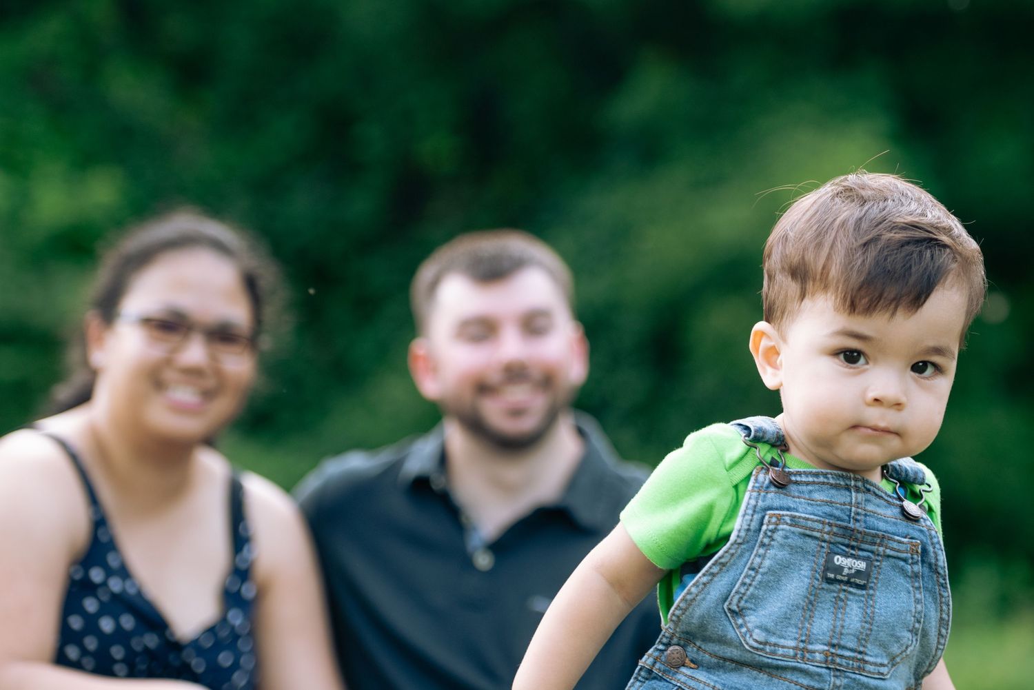 A young child in overalls explores outdoors on a sunny summer day.