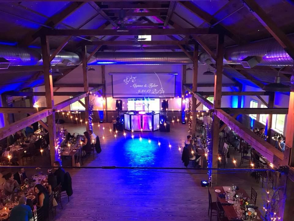 Large event venue with blue uplighting and exposed wooden beams creating an atmospheric ambiance.