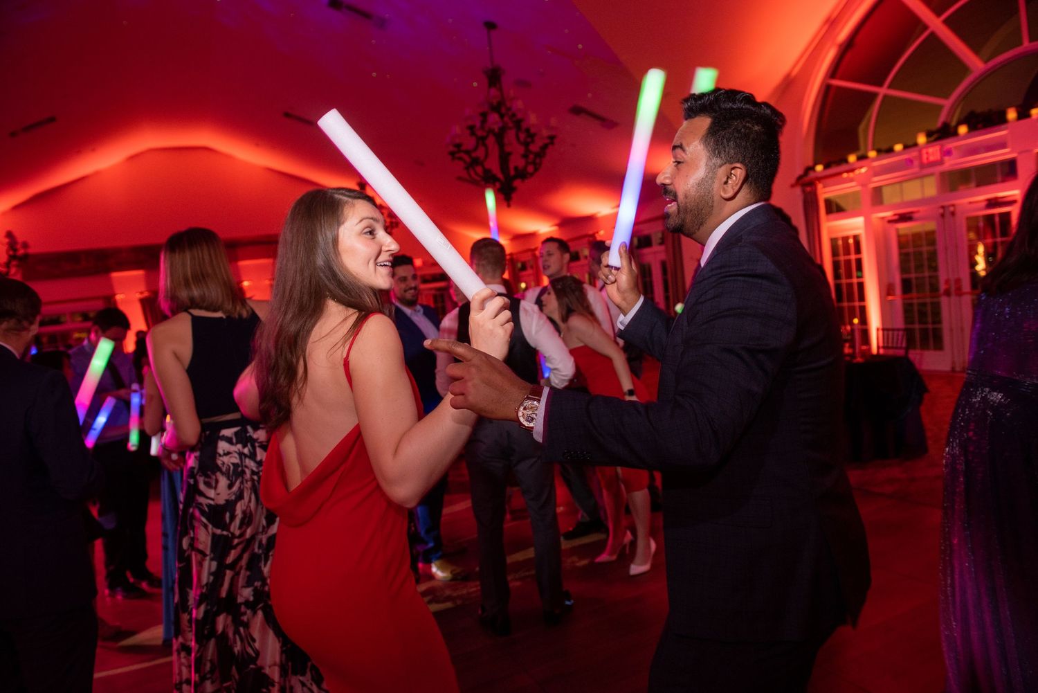 Wedding party guests dancing with light sabers under dramatic red lighting effects.