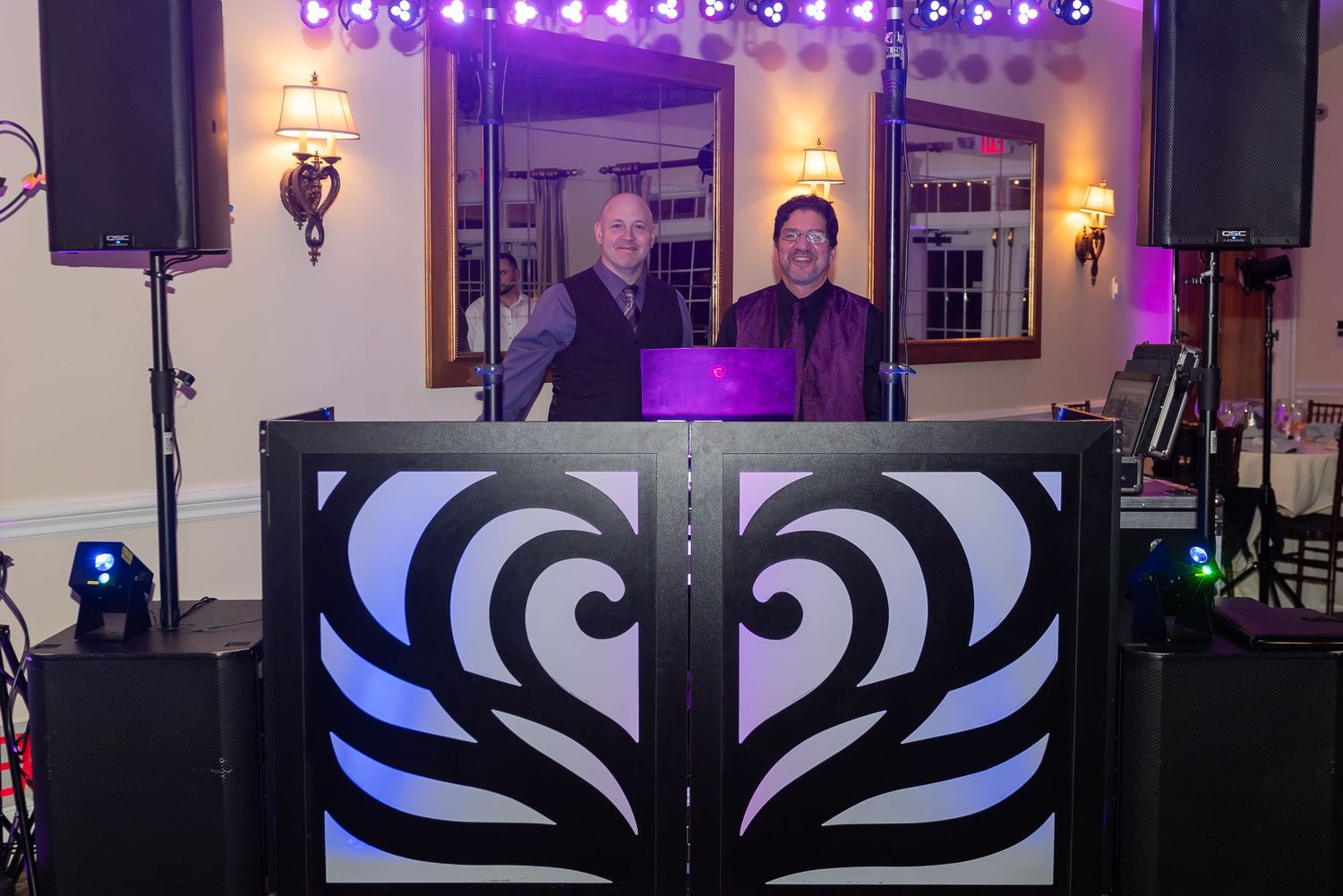 Professional DJ setup with black and white geometric design booth and purple accent lighting.