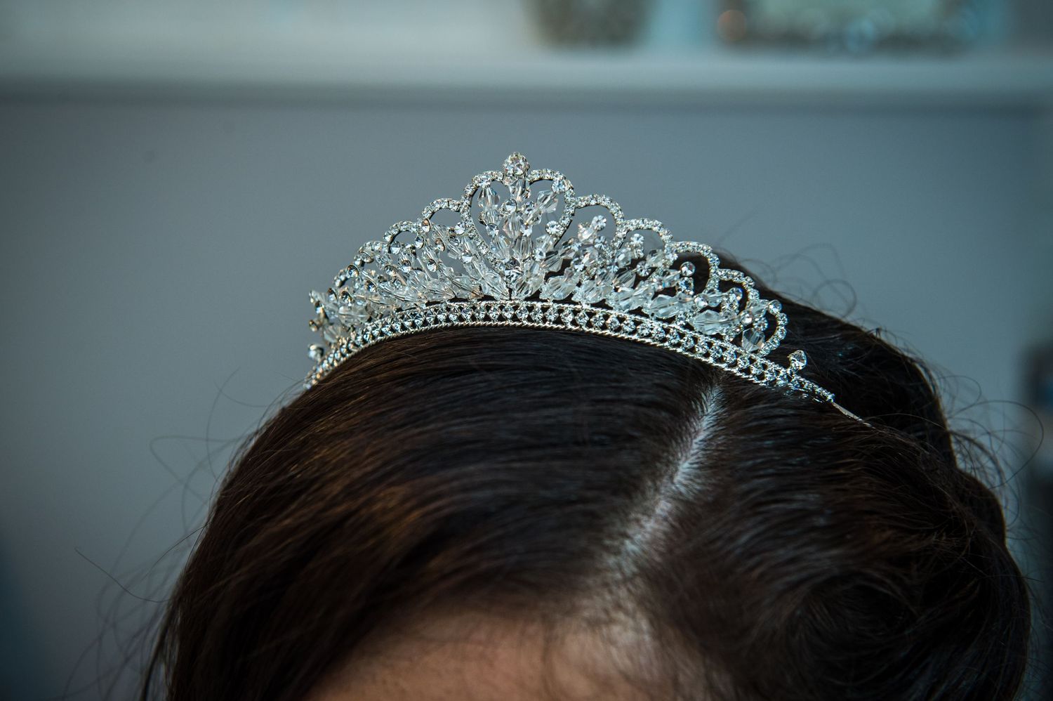 Elegant tiaras and formal hair styling details in a soft-lit setting.
