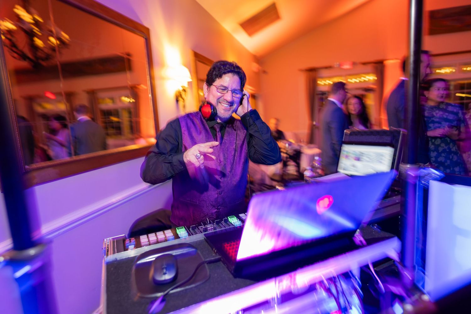 DJ performs at wedding reception with vibrant purple lighting effects.