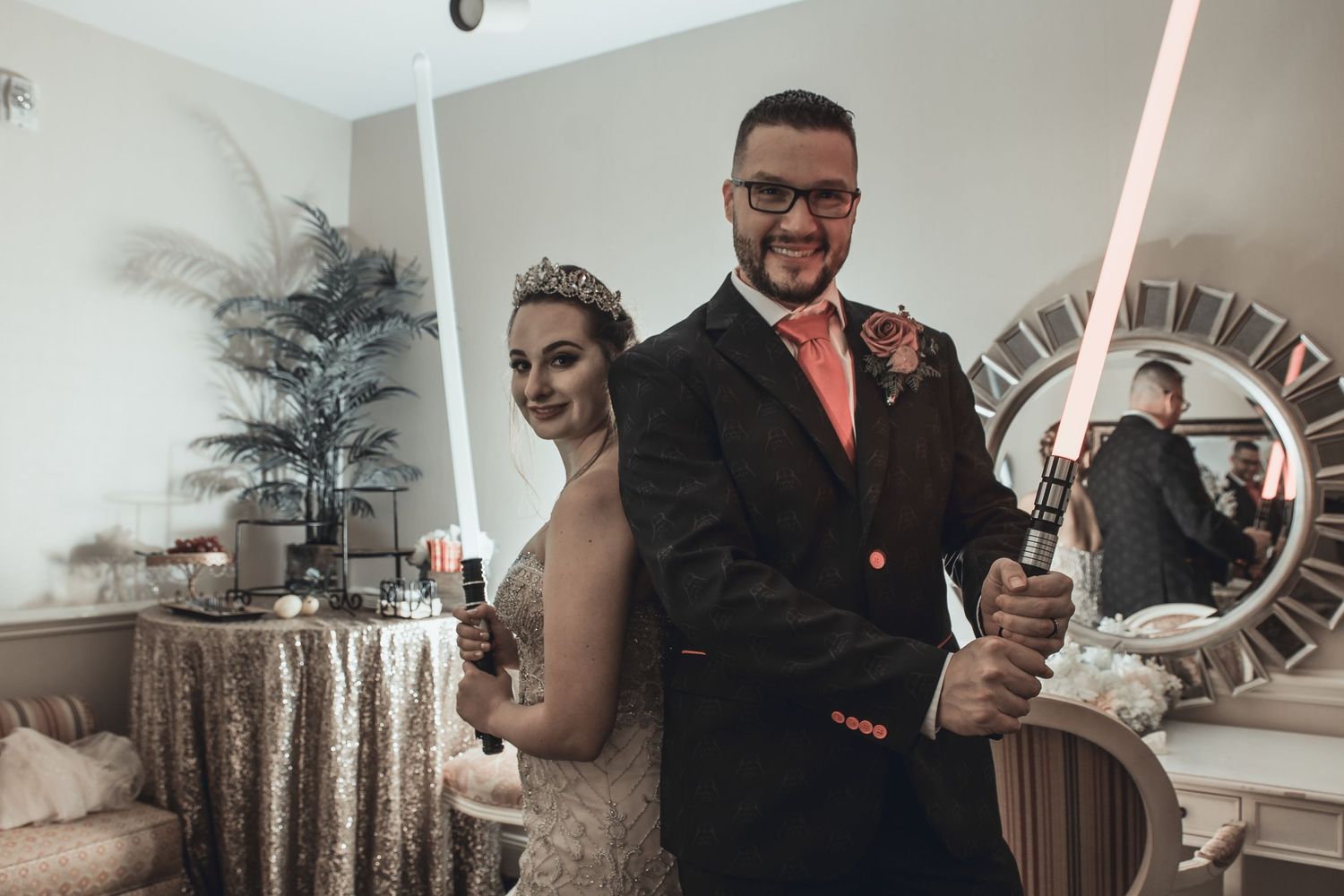 Wedding couple wielding lightsabers in a modern indoor setting with decorative elements.