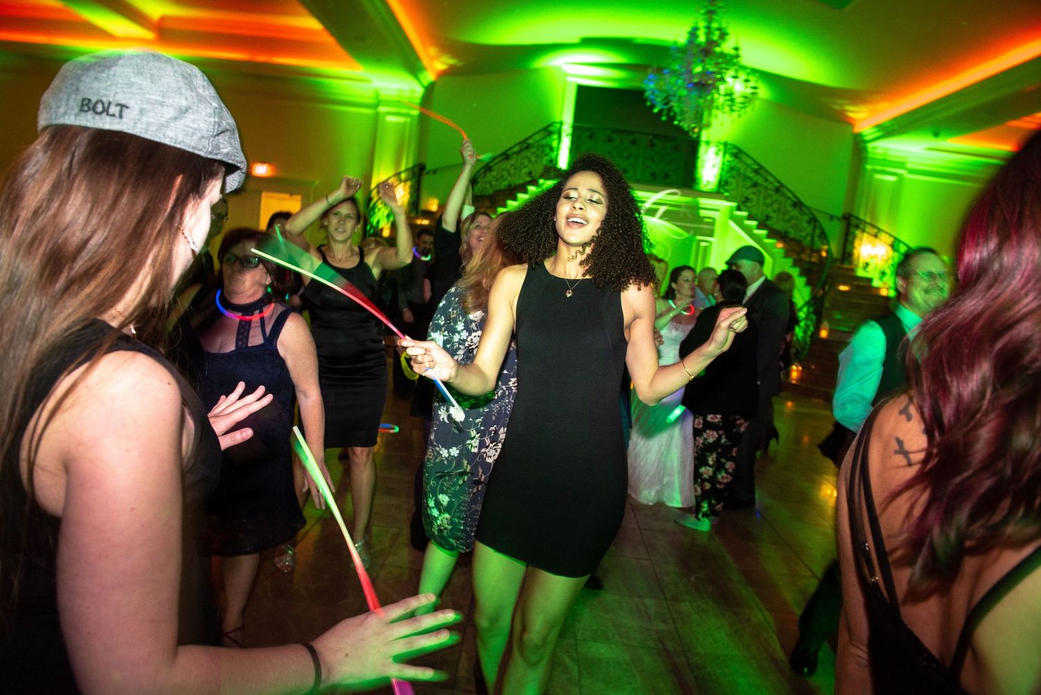 Wedding reception dance party with dynamic green and orange lighting effects.