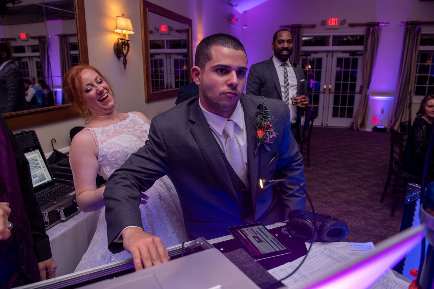 Wedding DJ booth setup with purple ambient lighting in an elegant ballroom setting.