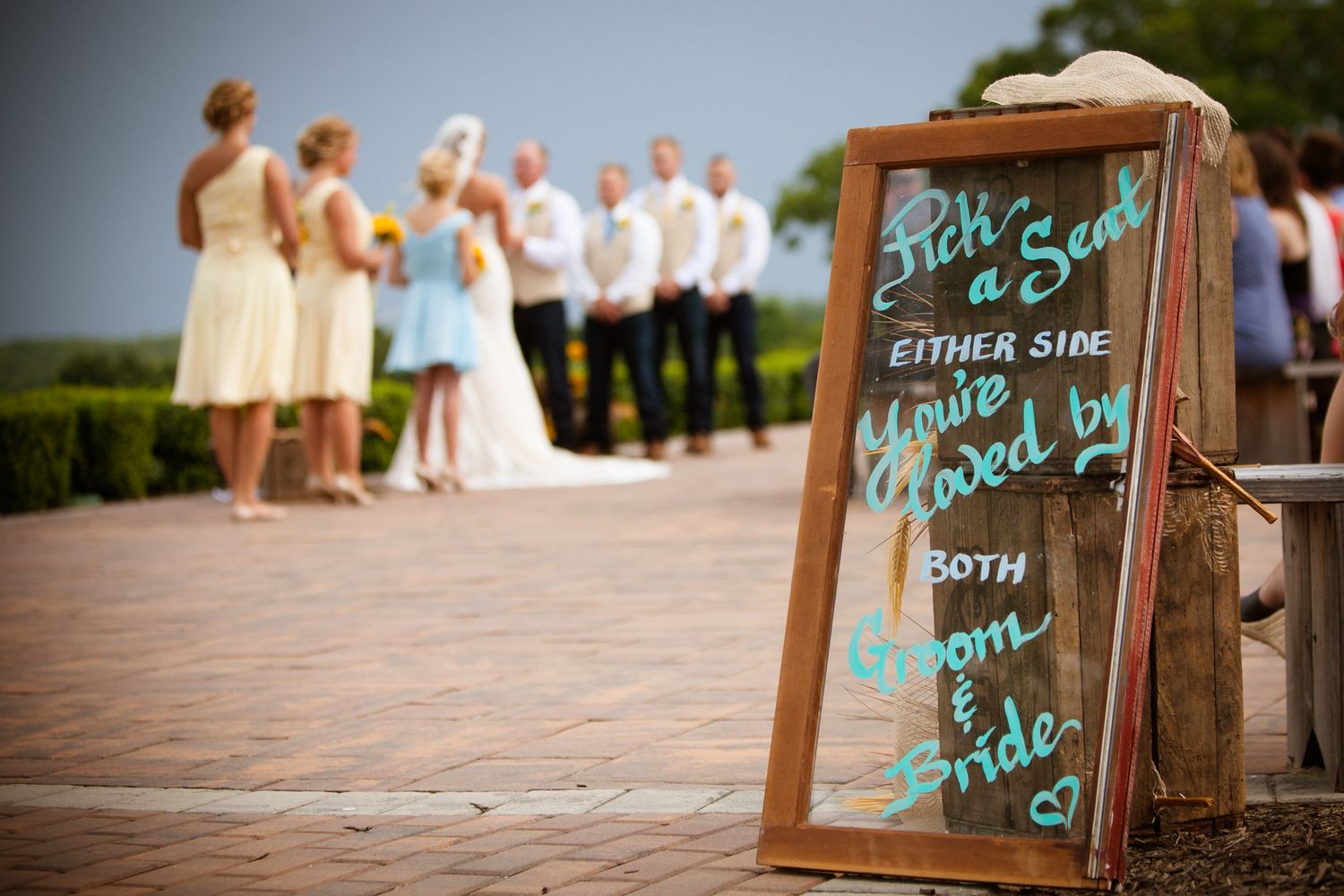 Rustic wooden signs with teal lettering displayed at an outdoor wedding venue.