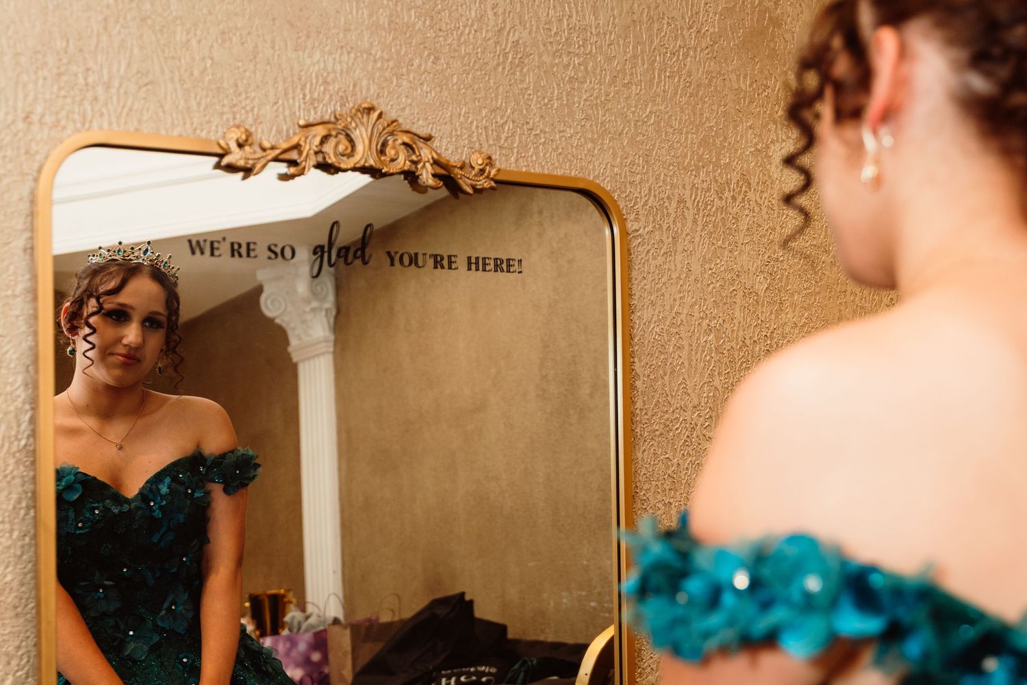 Getting ready scene reflected in a vintage mirror with teal dress visible.