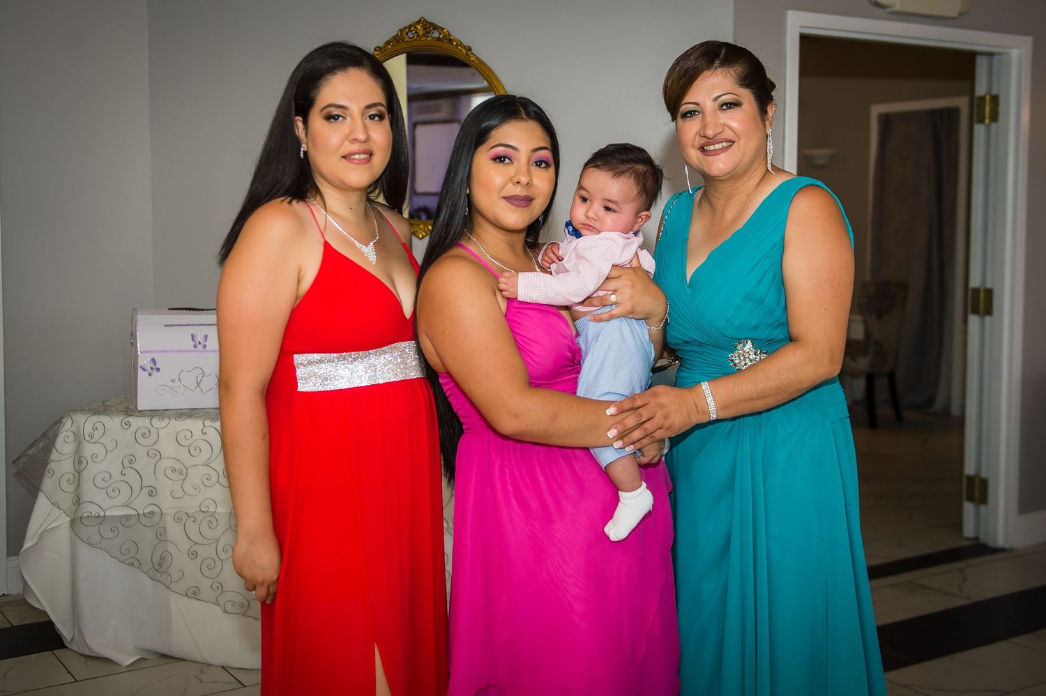 Family members pose together in vibrant formal dresses at a celebration.