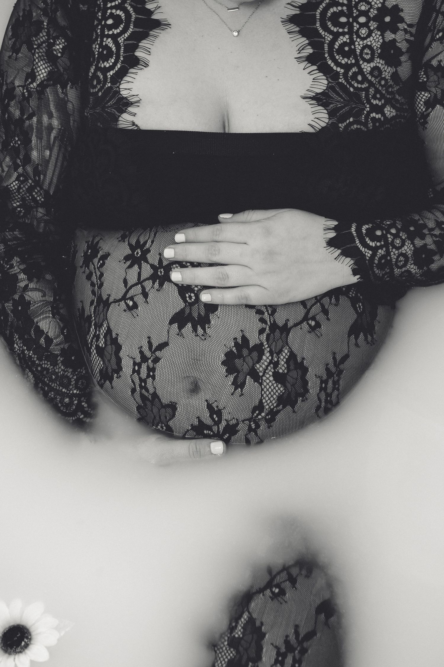 Artistic black and white milk bath photography featuring delicate black lace and floral elements.