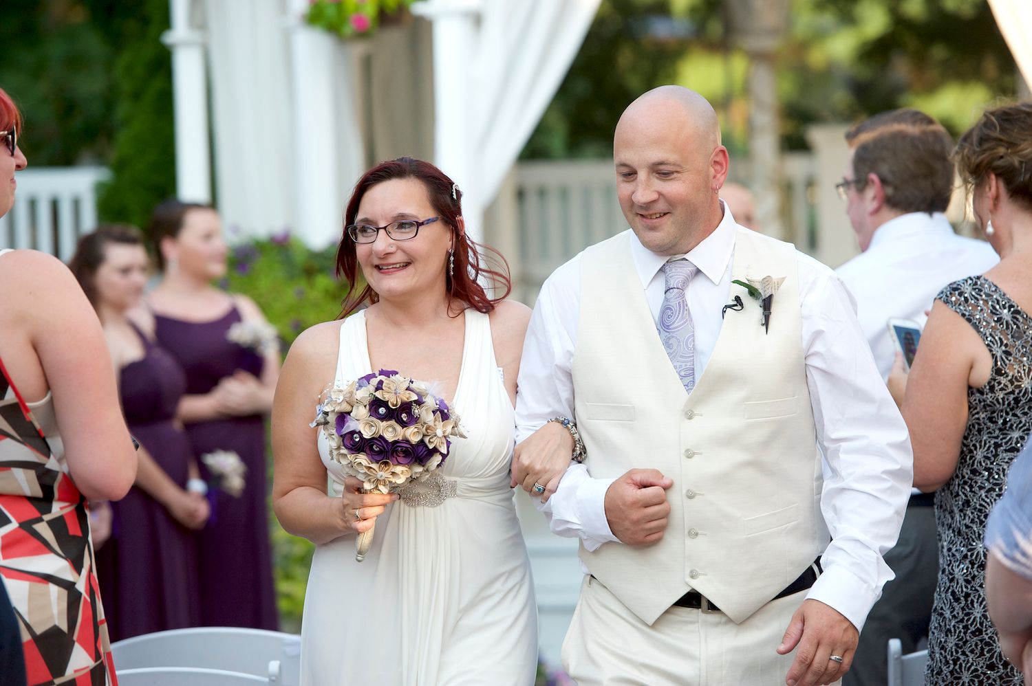 Wedding party members pose together on an outdoor patio with white columns.