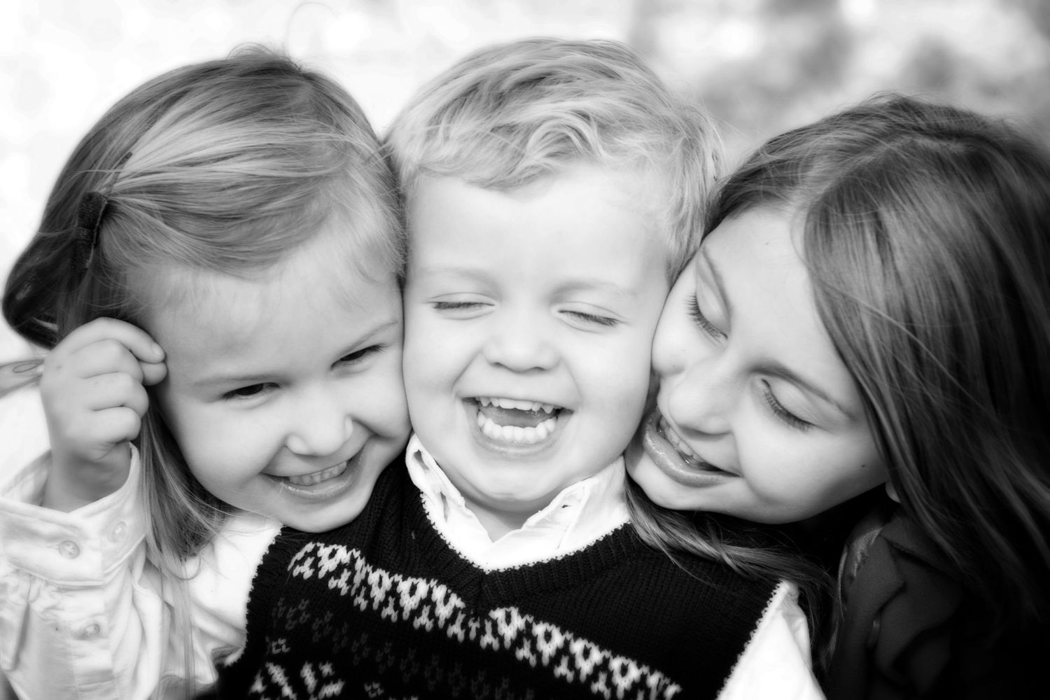 Black and white close-up portrait of children laughing and embracing.