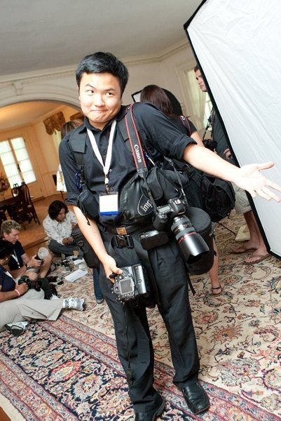 A photographer with professional camera gear and lighting equipment at an indoor event.