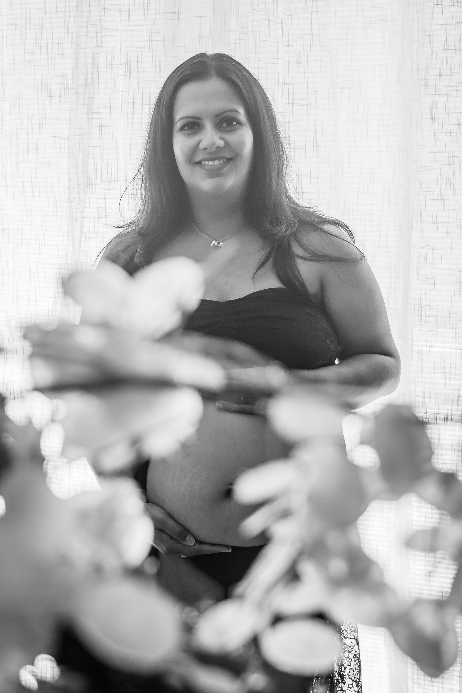 Black and white maternity portrait with soft window lighting.