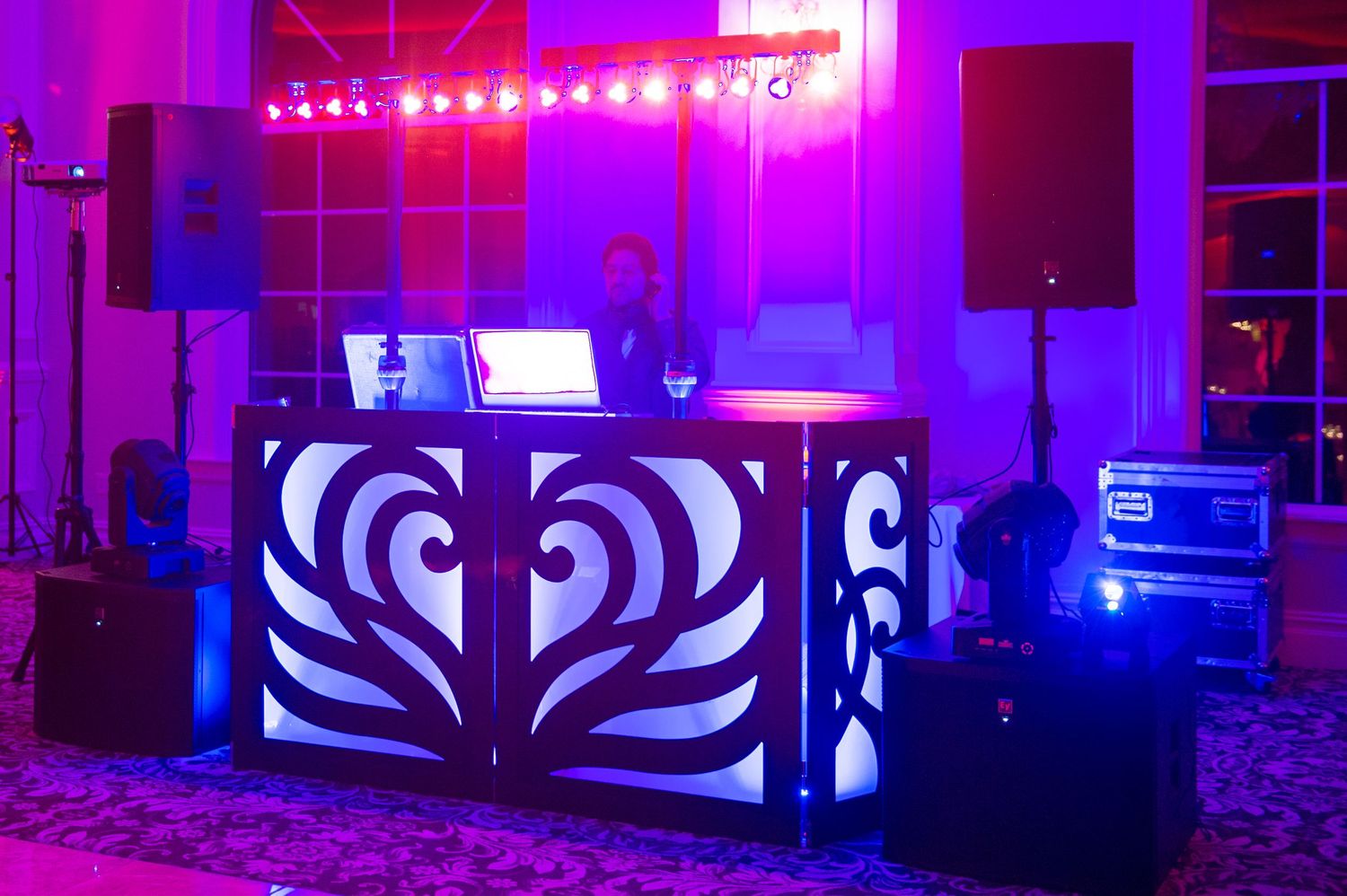DJ booth setup with vibrant purple and blue lighting effects at a wedding reception.