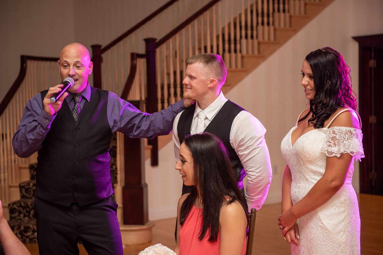 Wedding reception entertainment with guests playing party games in an elegant venue with wooden staircase.
