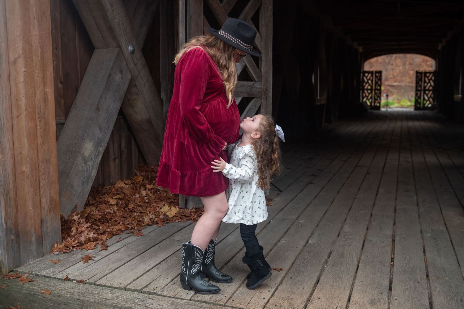 People in period clothing interact on a wooden boardwalk in low light.