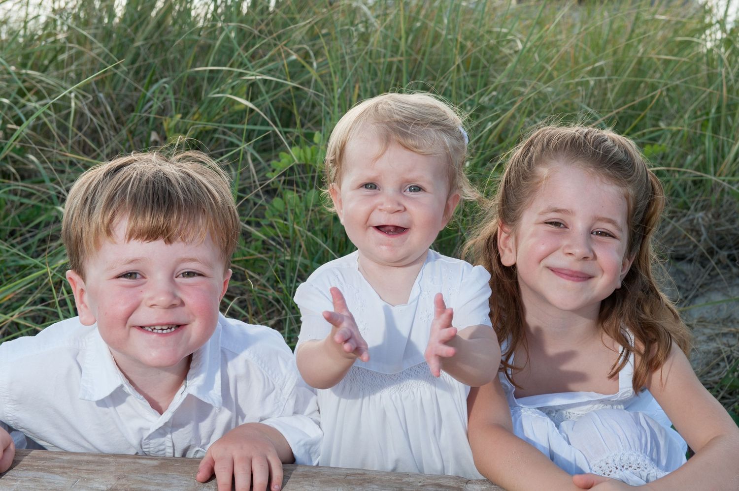 Children laying in grass while smiling and laughing together outdoors.