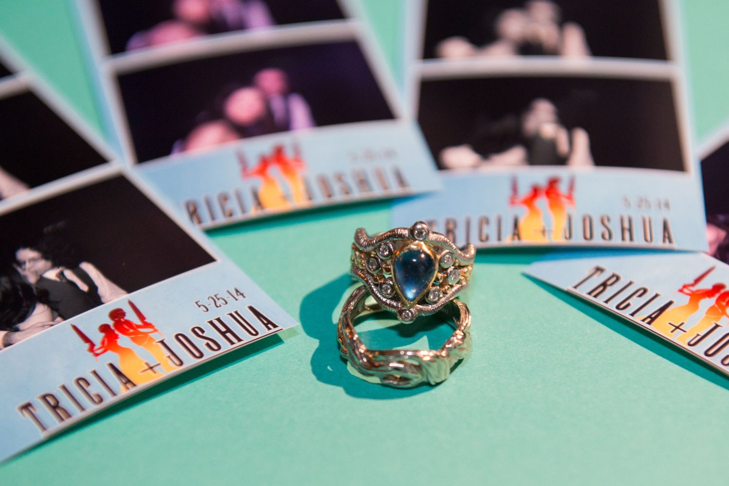 Wedding rings displayed on mint green surface with decorative cards.