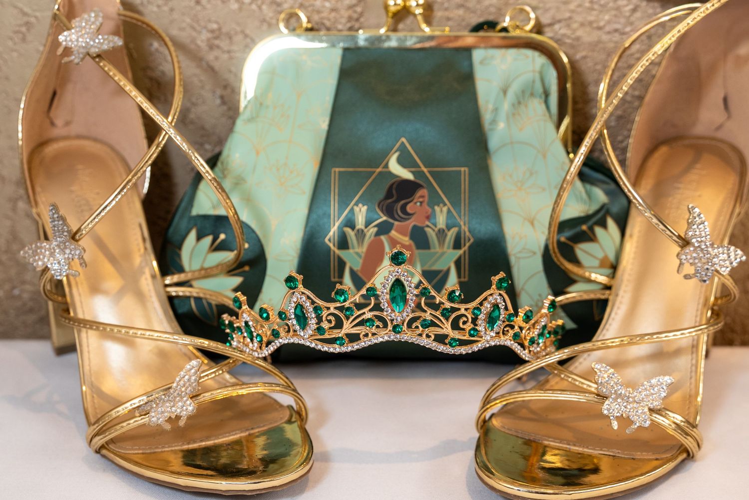 Gold strappy formal heels with crystal embellishments displayed on textured surface.