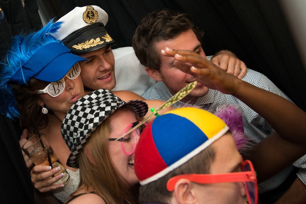 Fun party crowd wearing colorful hats and accessories while celebrating at a lively event.