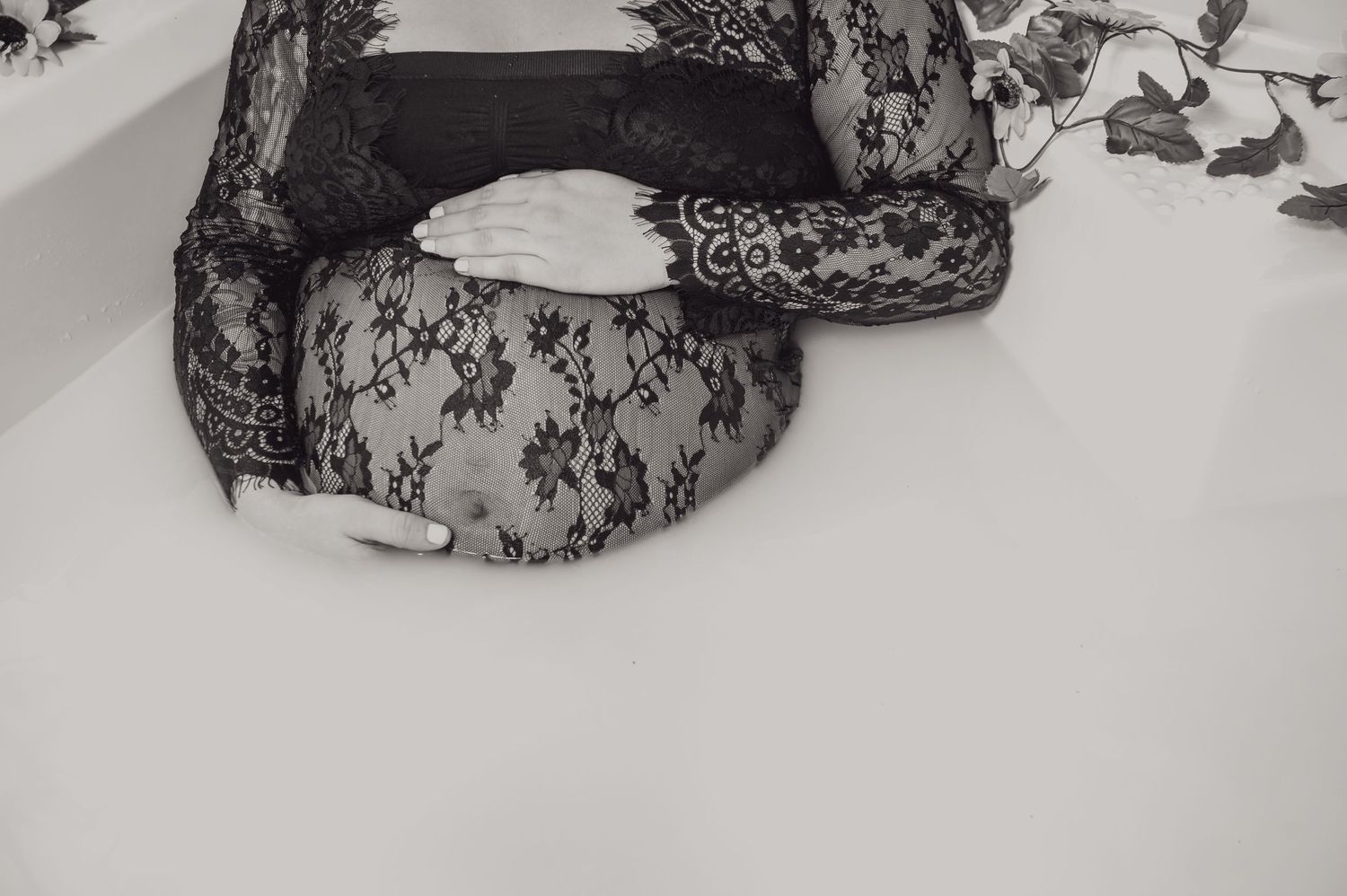 Ethereal milk bath portrait with black lace details and soft lighting effects.