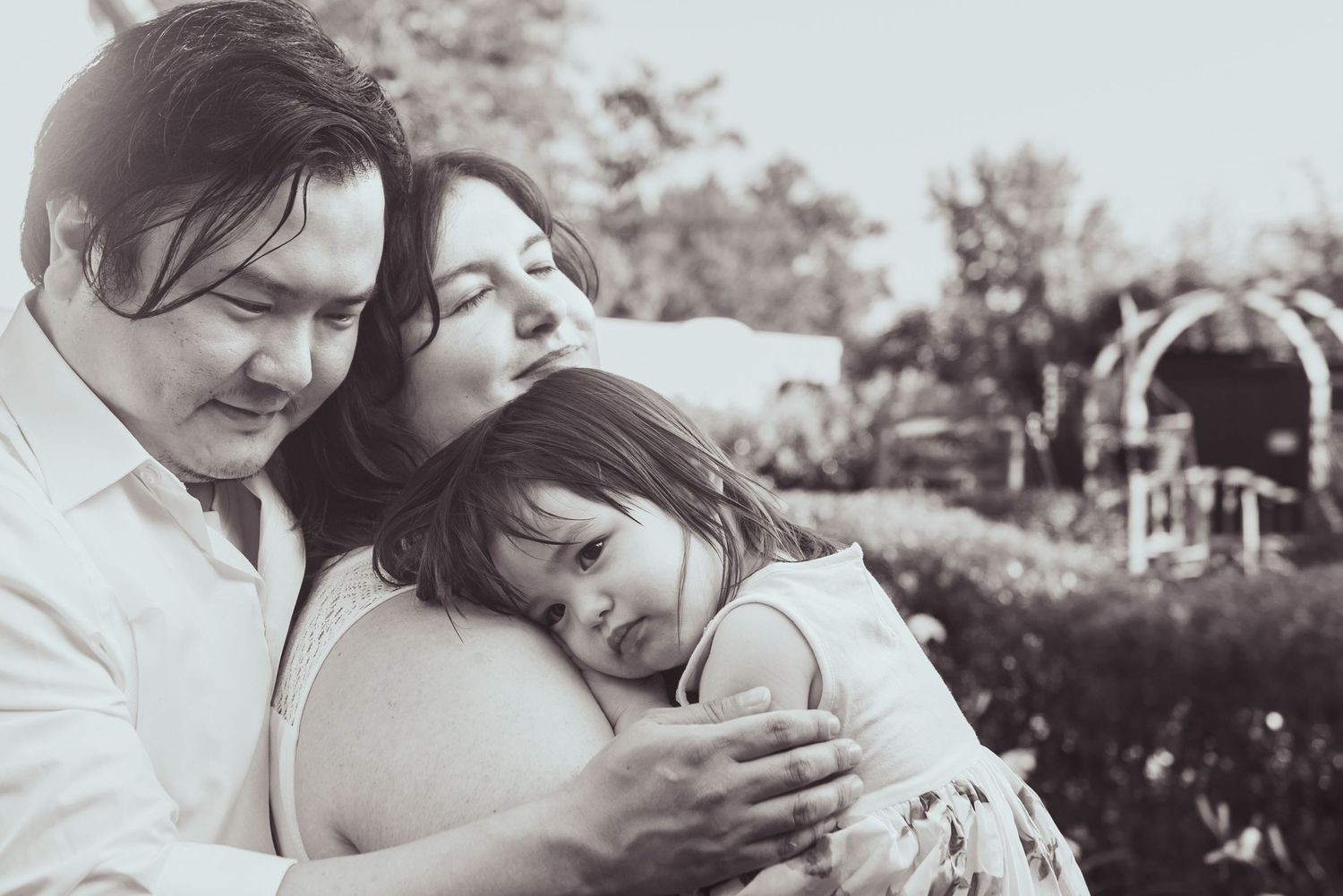 An intimate black and white portrait capturing a tender embrace between family members.