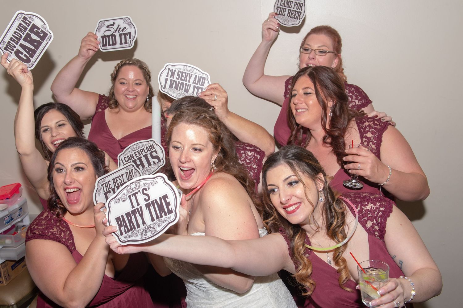Wedding party holding up fun photo props and signs during group photo session.