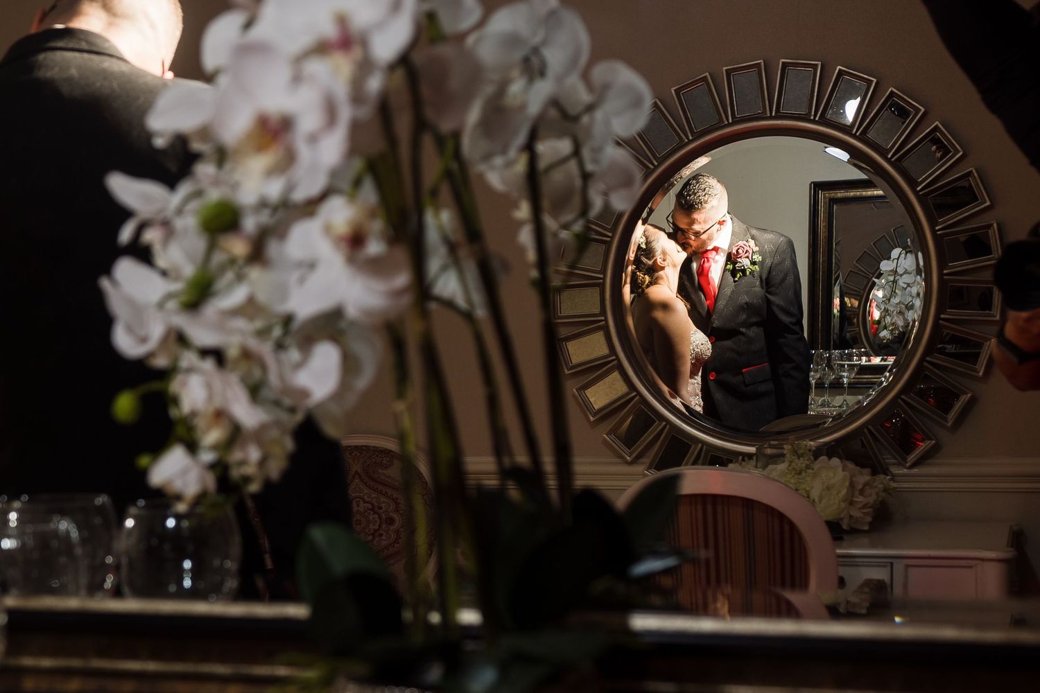 Artistic wedding detail shots with white orchids and mirrors creating reflective compositions.