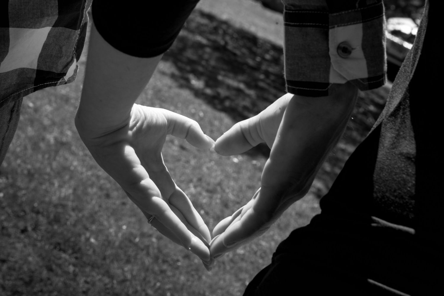 Two hands forming a heart shape silhouetted against a bright background.