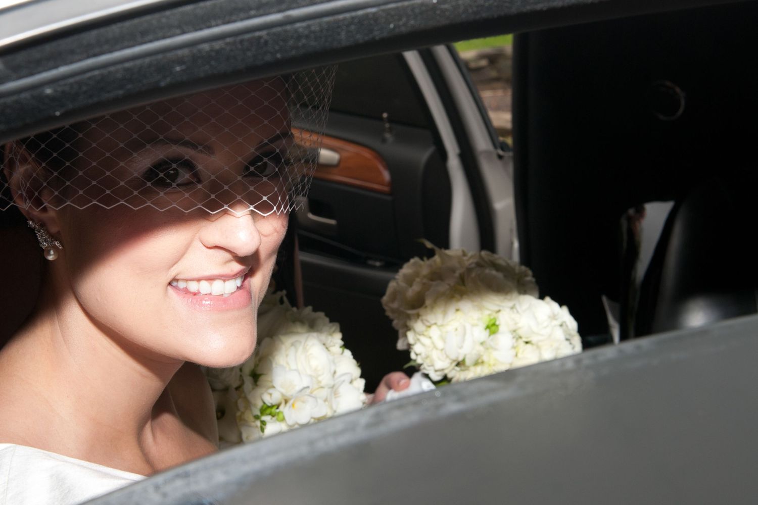 Wedding day moments captured through car windows with white bouquets visible.