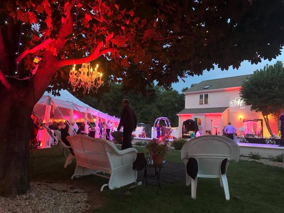 Outdoor venue at dusk illuminated with dramatic red lighting and white chairs.