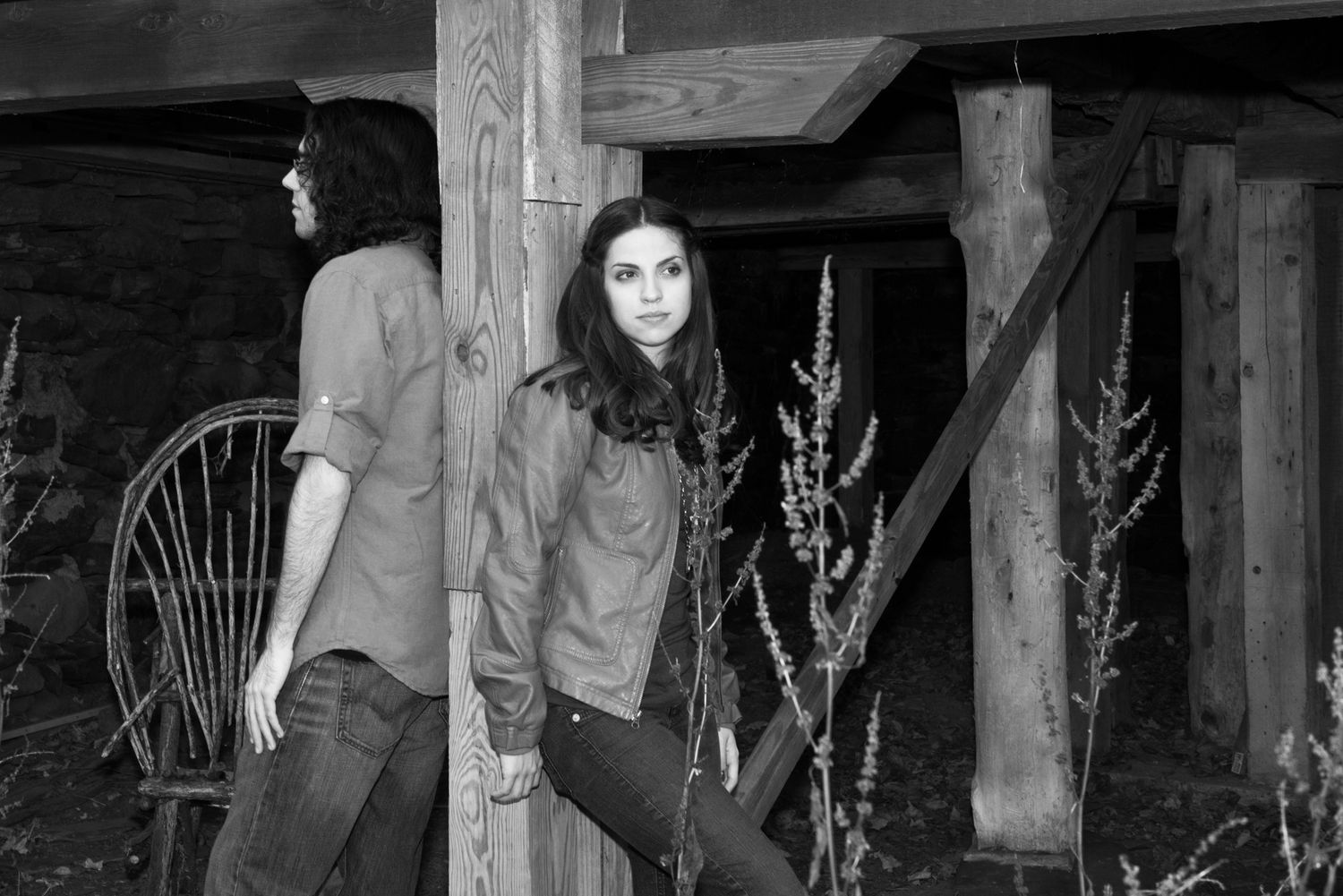 Artistic black and white portraits taken in a rustic wooden setting with dramatic lighting.