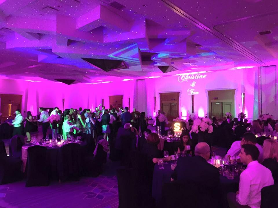 Large reception hall with purple ambient lighting and guests mingling at tables.