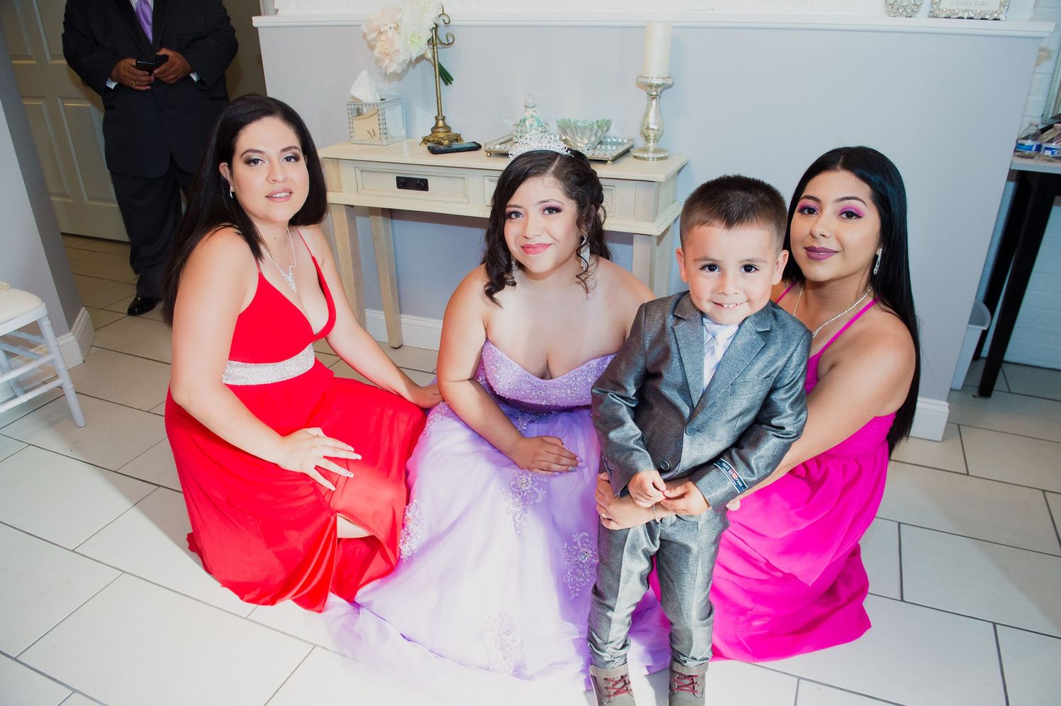 A group celebrates in formal attire with colorful dresses at an indoor event.
