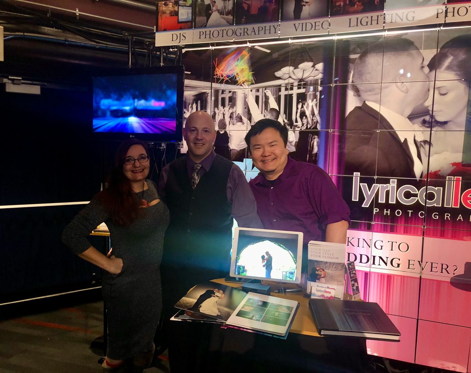 People gathered at a dimly lit venue with pink lighting and electronic displays visible in the background.