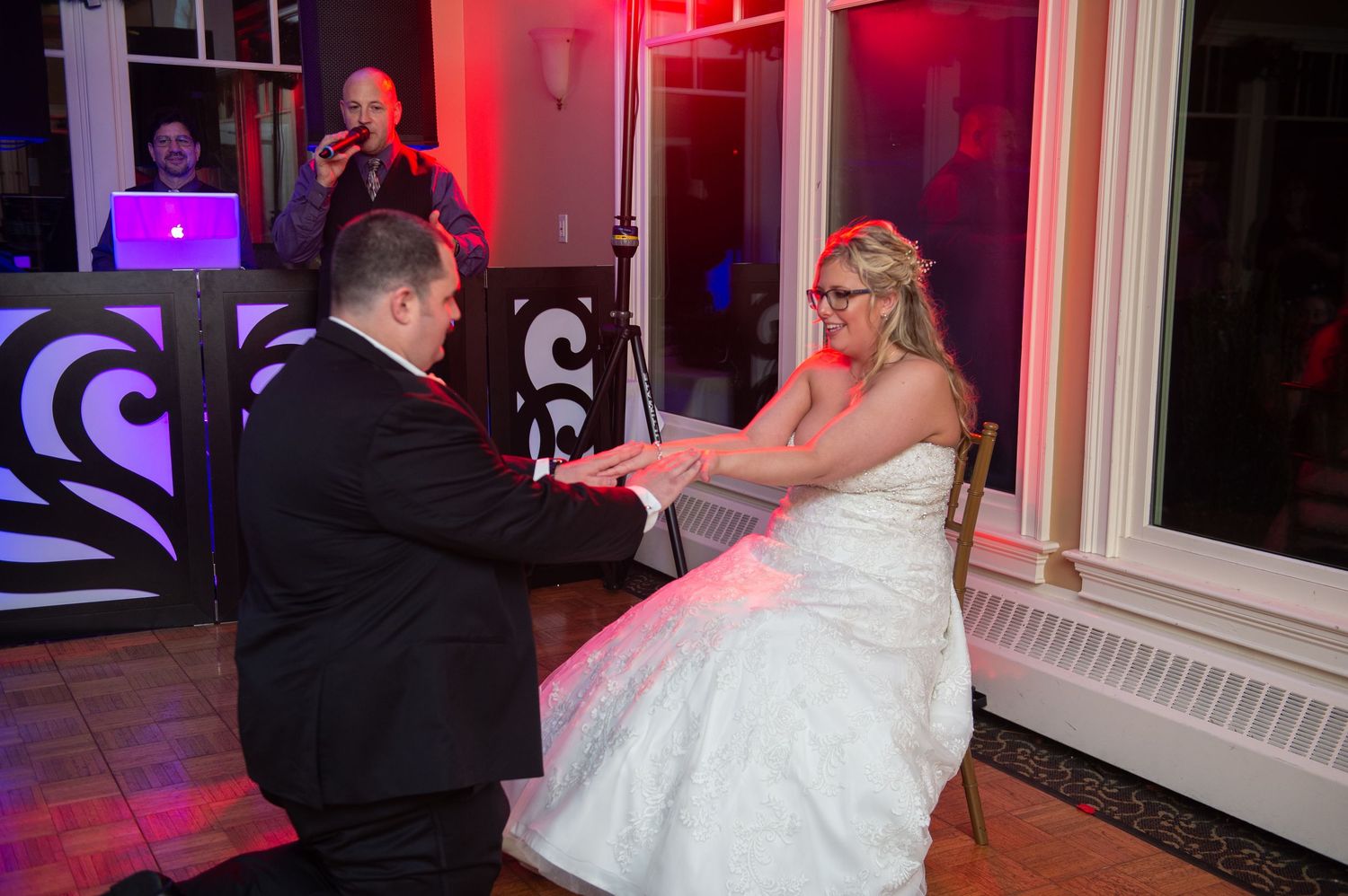 Wedding reception venue decorated with dramatic pink and purple lighting effects.